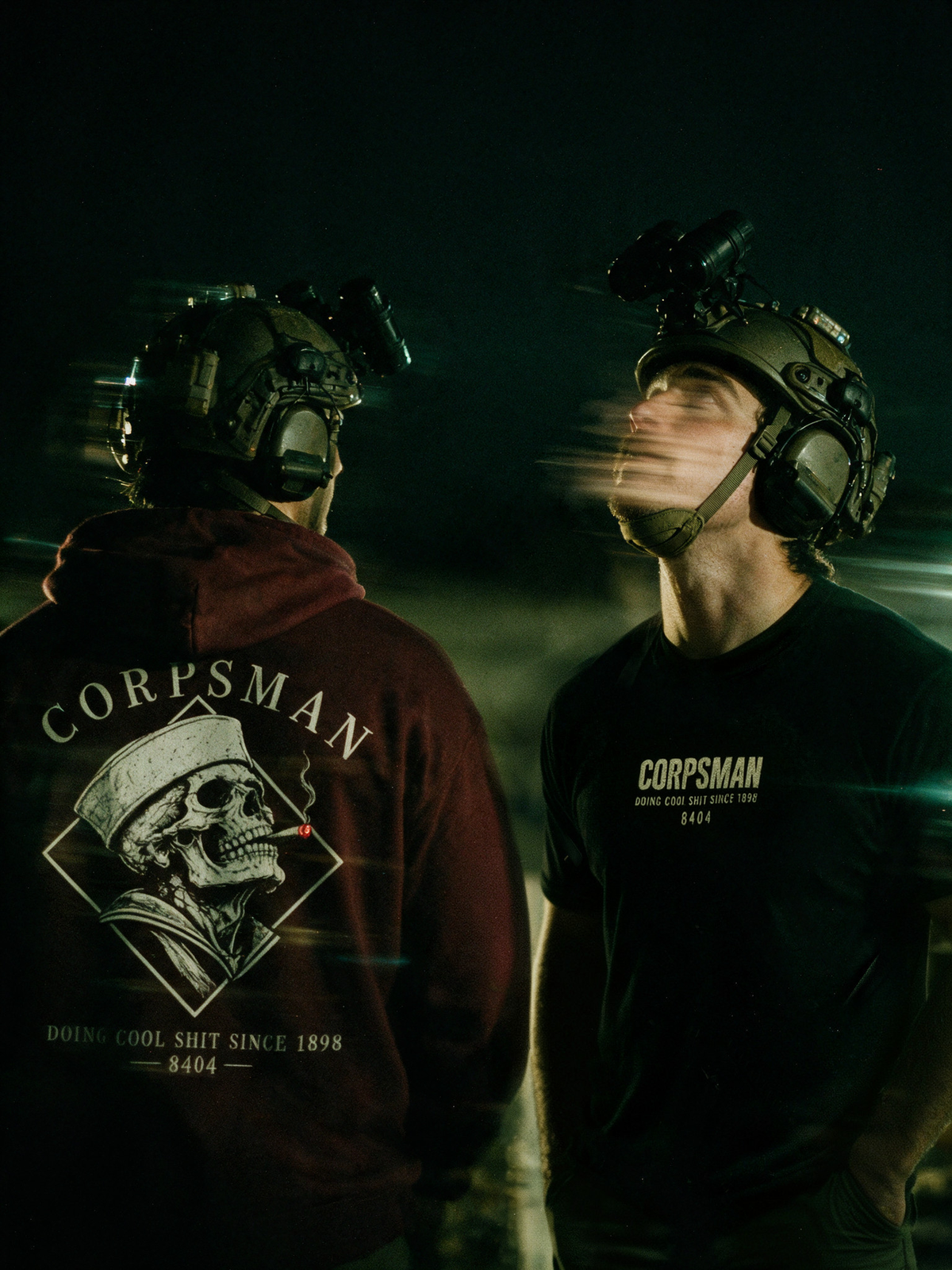 Corpsman 8404 maroon hoodie back and black T-shirt front in a cinematic nighttime scene.
